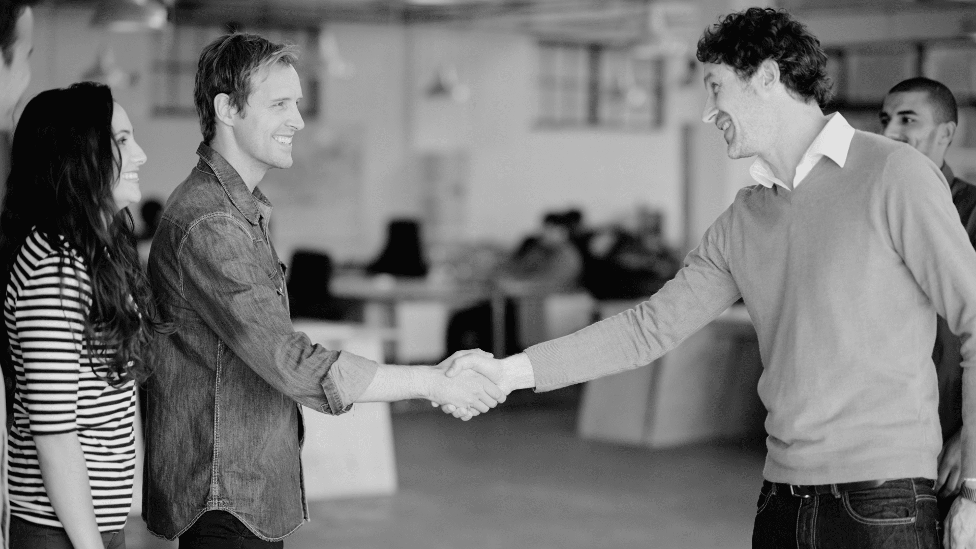 Businessmen greeting each other in open plan office